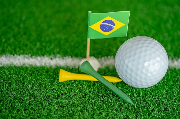 Golf ball with brazil flag and tee on green lawn or grass is\
most popular sport in the world