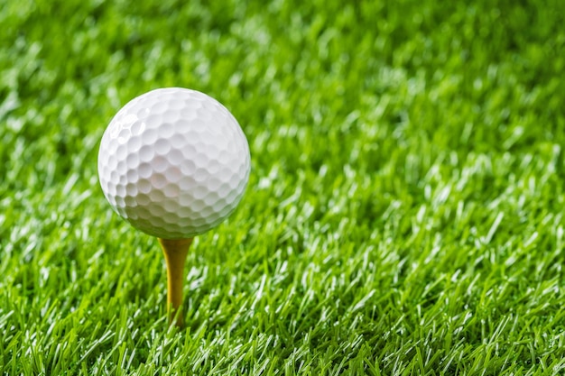 Golf ball with green grass background, on tee closeup.