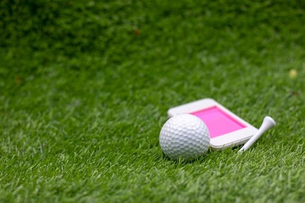 Photo golf ball with mobile phone on green grass.