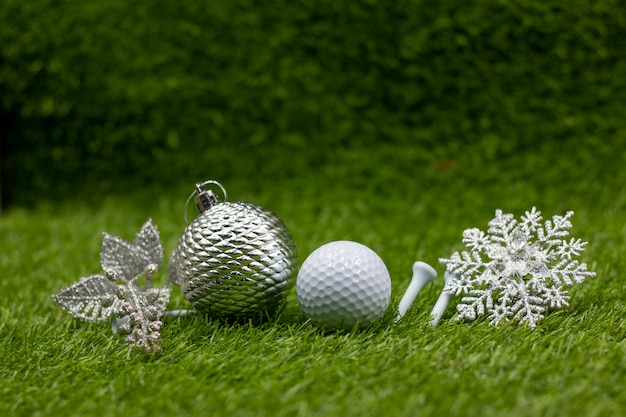 Golf ball with snow flake and christmas ornament are on green\
grass