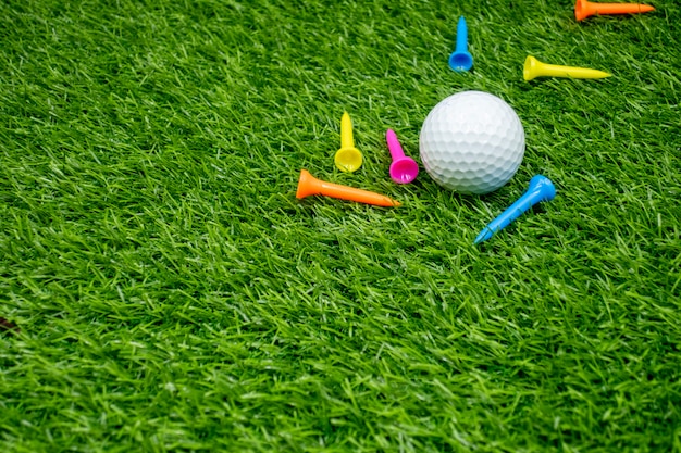 Photo golf balls and tees are on green grass.