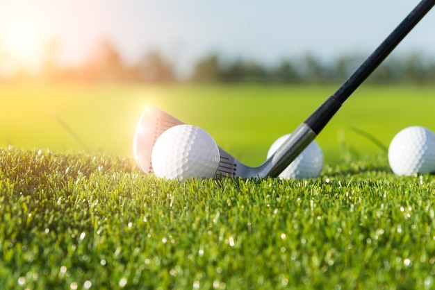 Photo golf club and ball in grass and sunset