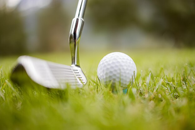 Golf club and ball on tee in front of driver