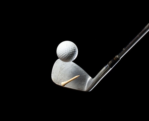 Golf club sand wedge with many tee off and golf ball over Black background isolated