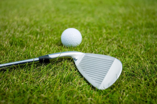 Golf clubs and ball on green grass background