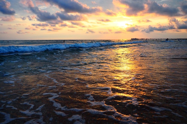 Golf en zonsondergang boven zee Prachtige zonsondergang Schuimende golven rollen over de zandkust Vityazevo Anapa Zwarte Zee Toeristisch kuuroord Mekka Avondlucht De stralen weerkaatsen op het water