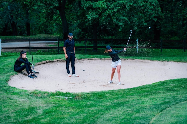 Golf lessons young woman having a golf lesson playing from sand bunker