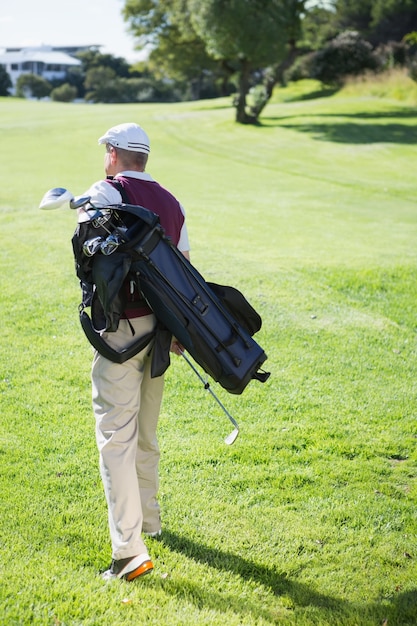 Foto giocatore di golf che trasporta la sua borsa e camminare