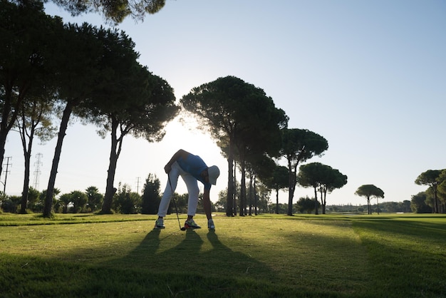 golf player hitting shot with club on course at beautiful morning with sun flare in background