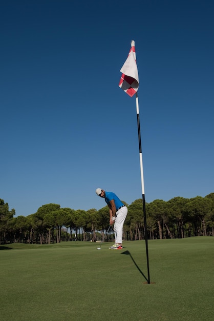 golf player hitting shot with driver on course at beautiful sunny day