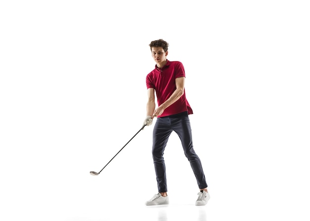白いスタジオの背景に分離された練習の赤いシャツのトレーニングのゴルフプレーヤー