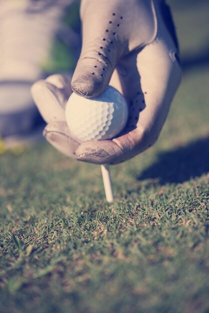 Foto giocatore di golf che mette la palla sul tee. bellissima alba sul paesaggio del campo da golf sullo sfondo