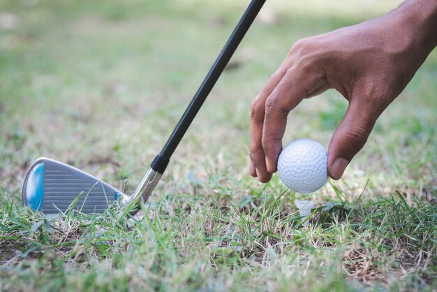 The golf player putting golf ball on tee against with a golf\
club