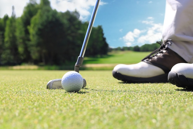 Golf player at the putting green hitting ball into a hole.