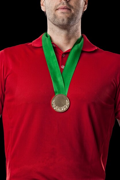 Giocatore di golf in una camicia rossa che celebra con una medaglia d'oro, su uno sfondo nero.