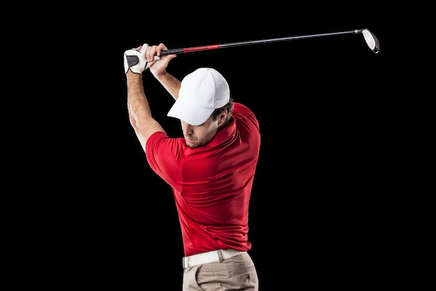 Golf Player in a red shirt taking a swing, on a black Background.