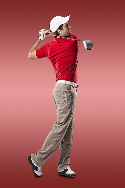 Golf Player in a red shirt taking a swing, on a red Background.