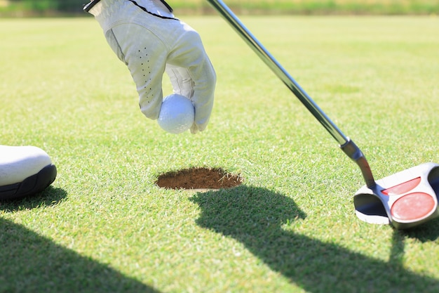 Il giocatore di golf prende la palla fuori dal buco.