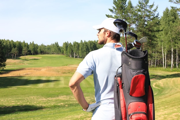 Golf player walking and carrying bag on course during summer\
game golfing.