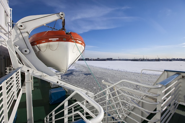 Golf van Finland bedekt met ijs op de zeehaven van St. Petersburg en een reddingsboot van een schip op de voorgrond. Rusland