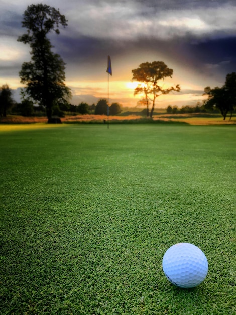 Golfbal op het veld tegen de hemel bij zonsondergang