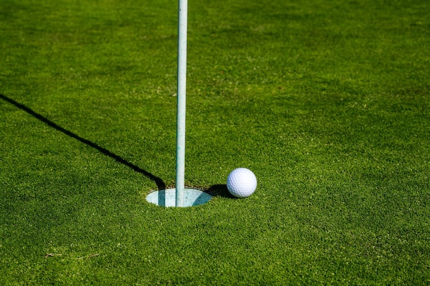Golfbal op lip van kop op grasachtergrond golfgat golfbal op het gazon sport golfachtergrond wi