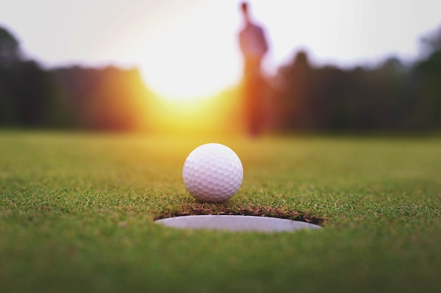 Golfballen en golfclub op groen gras glanzend licht sunse