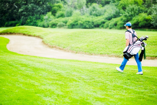 Golfer carrying his equipment on a beautiful sunny day