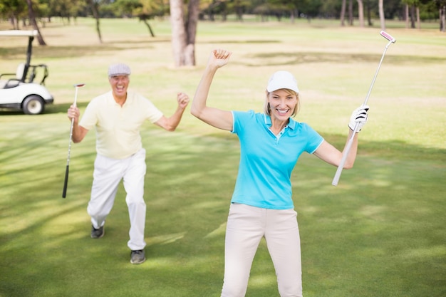 Golfer couple celebrating success while standing on field