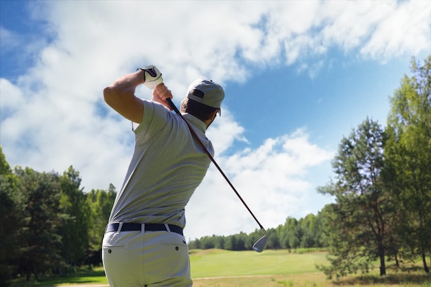 Golfer die golfschot met club op cursus raakt terwijl hij op zomervakantie is.