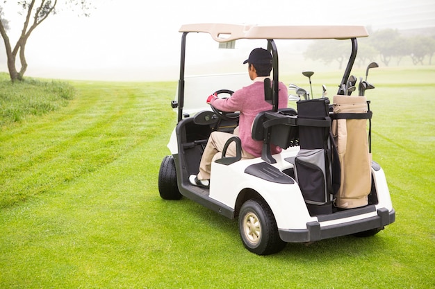 Giocatore di golf che guida nel suo golf buggy