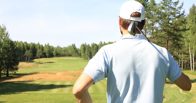 Golfer hits an fairway shot towards the club house.