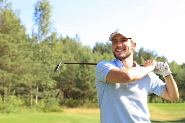 Golfer hits an fairway shot towards the club house.