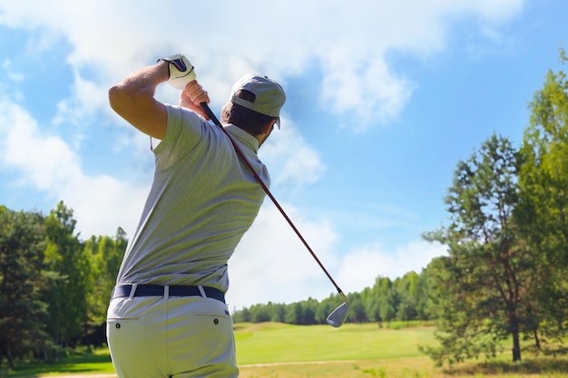 写真 夏休み中にコースでクラブとゴルフショットを打つゴルファー