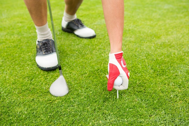 Golfer placing golf ball on tee