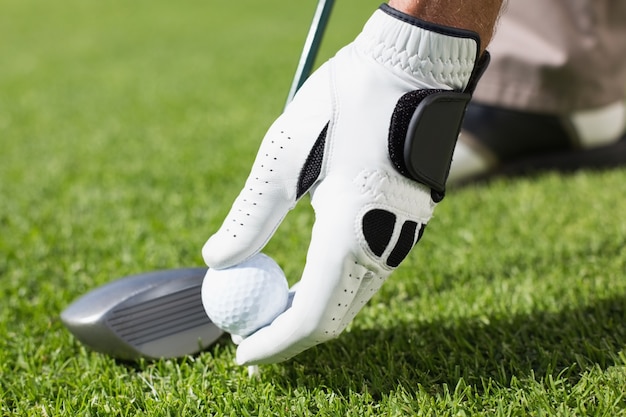 Golfer placing golf ball on tee