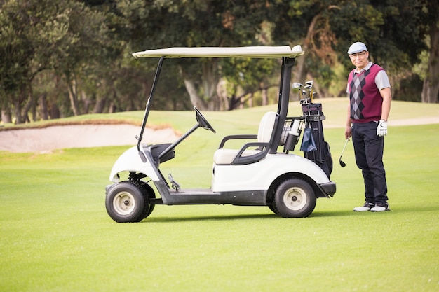 Golfer posing next to his golf buggy