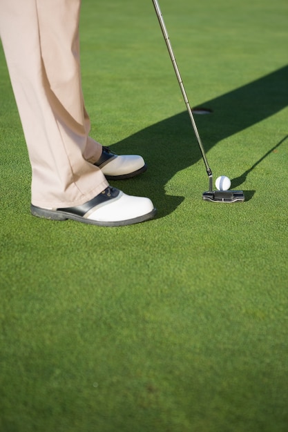 Golfer putting ball on the green