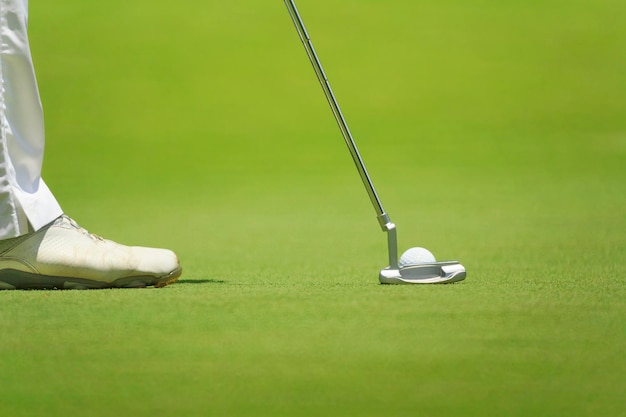 Golfer putting selective focus on golf ball