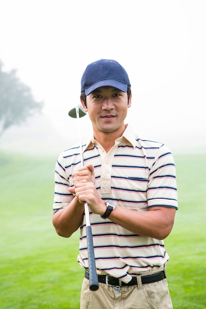 Golfer standing and holding his club smiling at camera