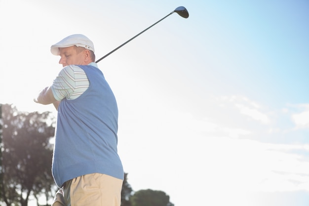 Golfer standing and swinging his club