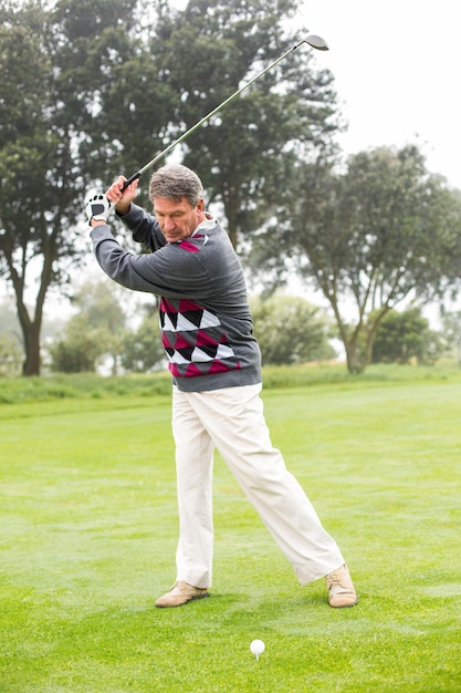 Foto giocatore di golf che oscilla il suo club sul corso