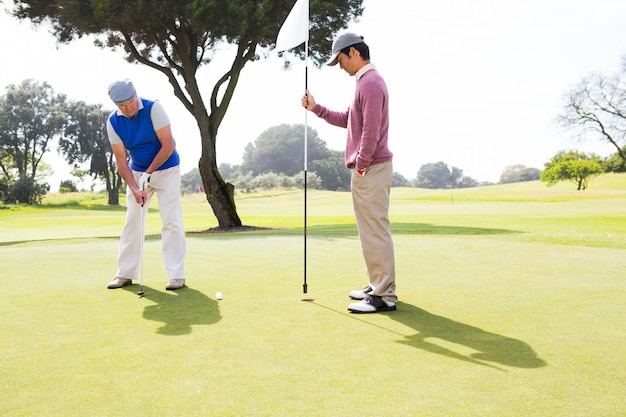 Golfer swinging his club with friend 