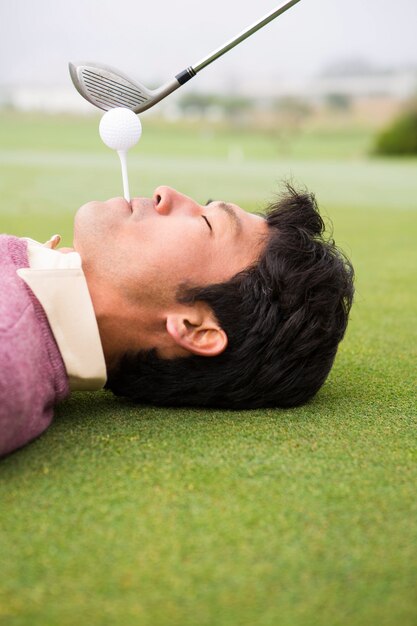 Golfer teeing off from lying man mouth 