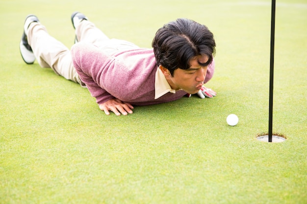 Игрок в гольф пытается щелкнуть мяч в отверстие