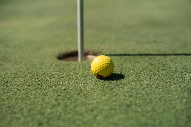 Golfgebied met gele bal dichtbij het gat