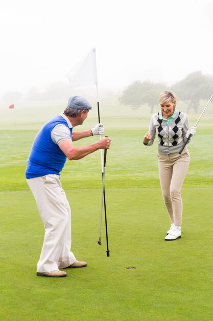 Golfing couple cheering on the putting green 