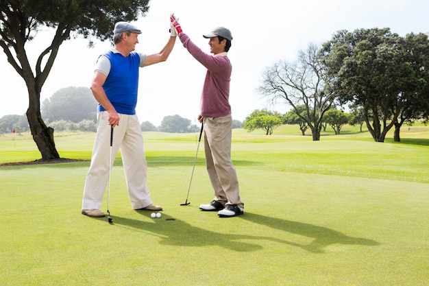 Golfing friends high fiving on the hole