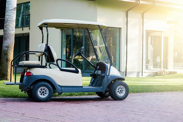 Golfkar staat geparkeerd in de buurt van het moderne huisje. Elektrische auto op de parkeerplaats van het resort