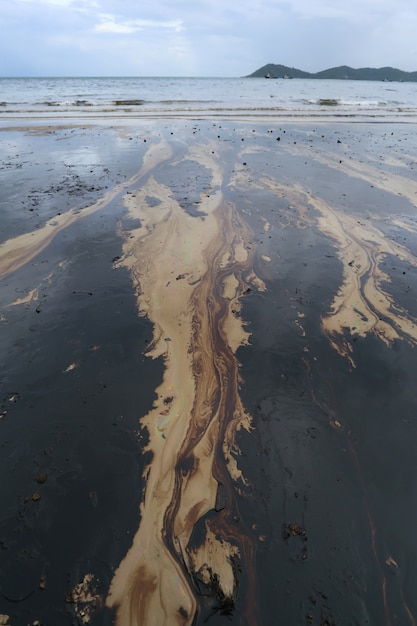 Golfolieverontreiniging wordt op een strand getoond